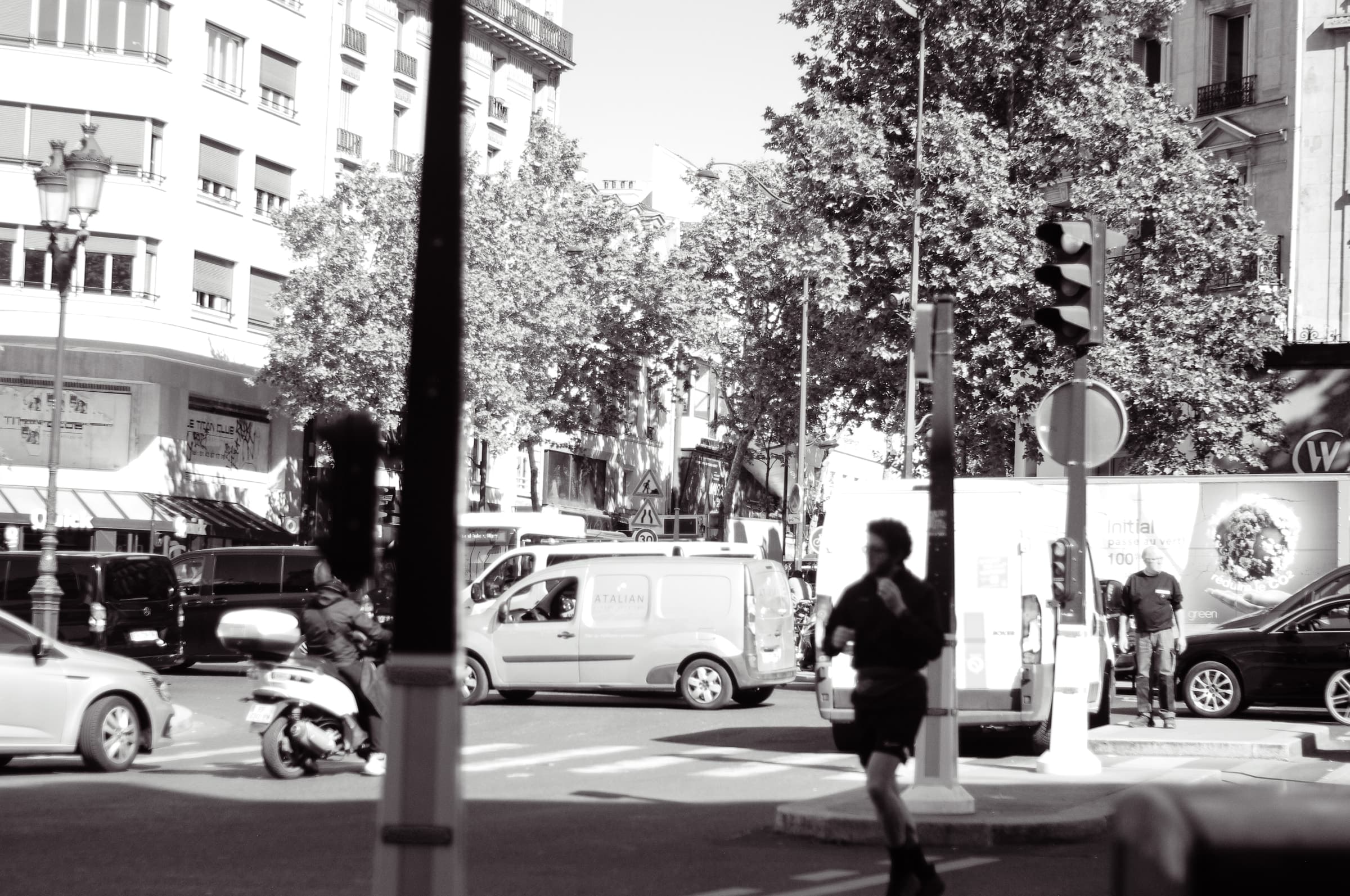 A lone pedestrian crossing the foreground with traffic in the distance