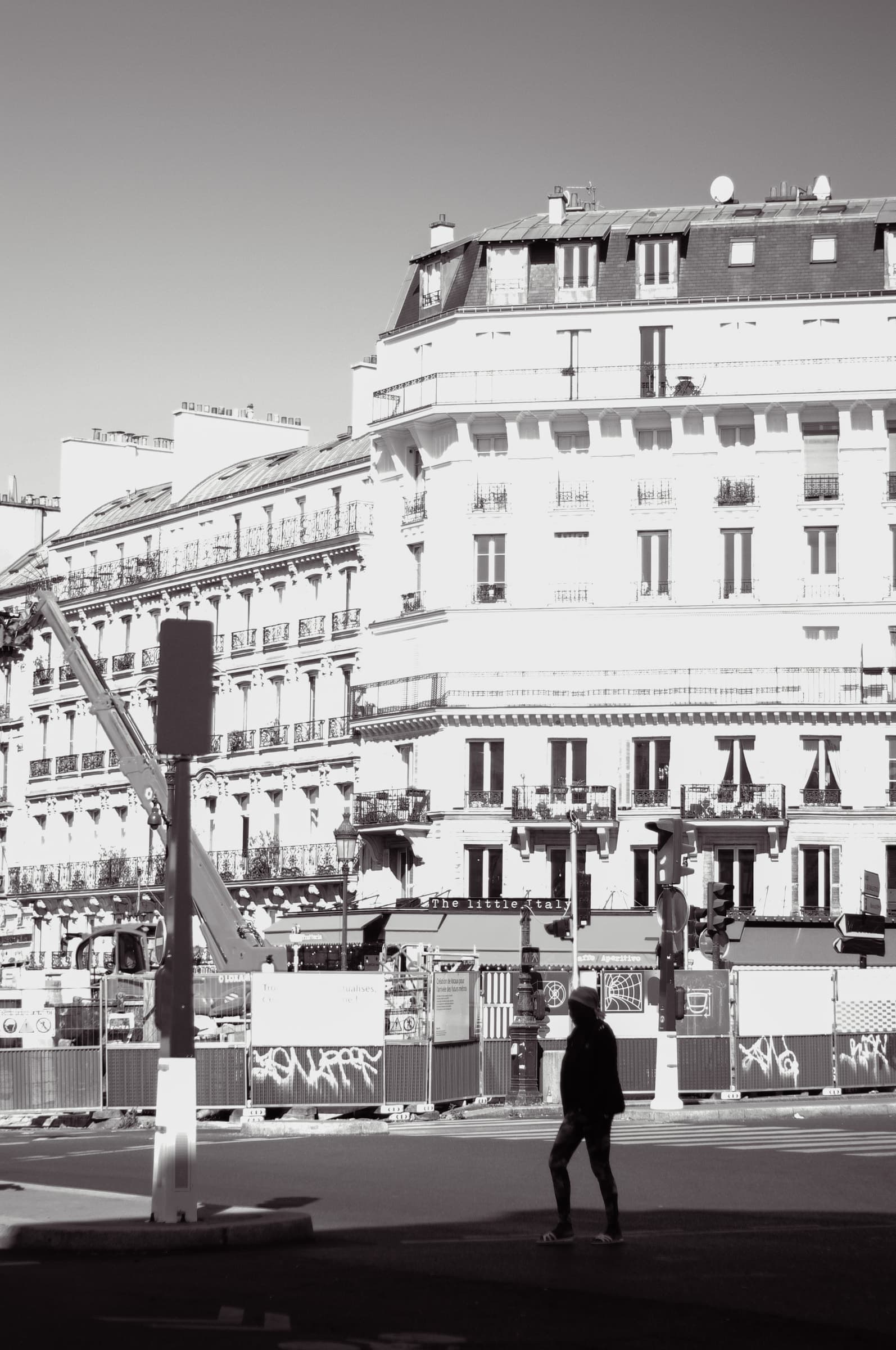 A pedestrian silhouetted against the square and surrounding Parisian buildings