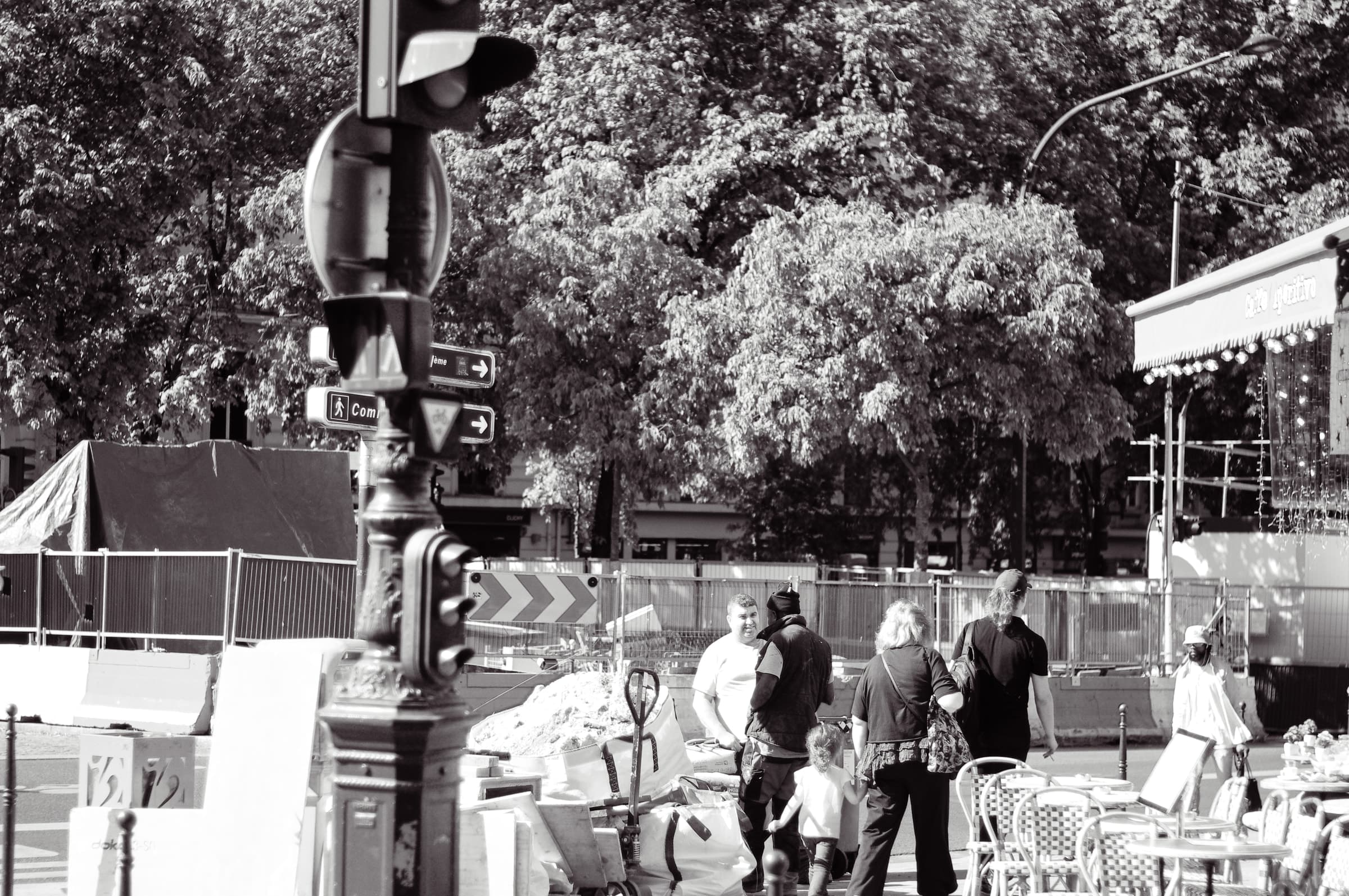 People walking beside construction barriers and a traffic light