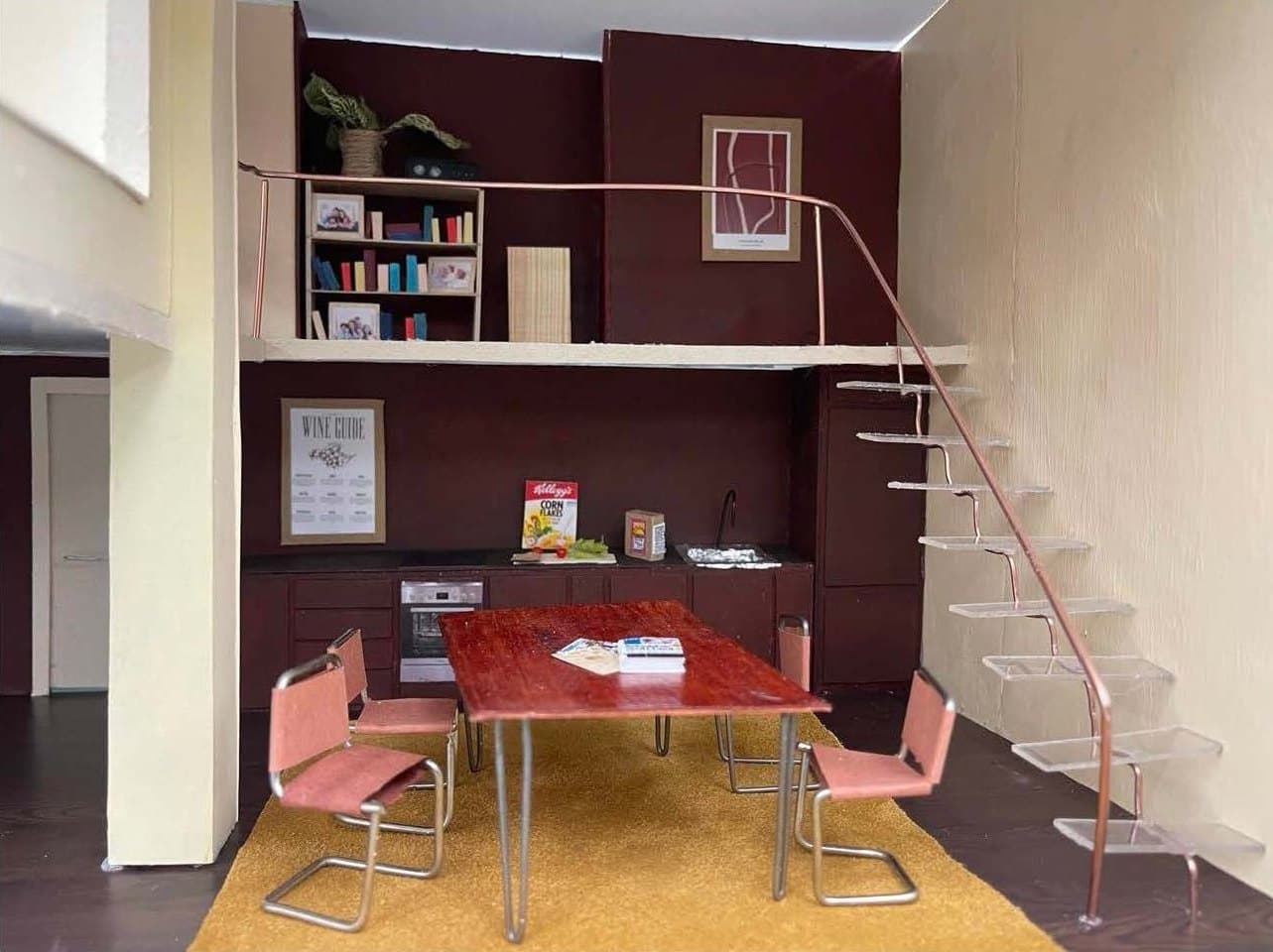 Model interior with a dining table, a mezzanine, and a light steel staircase against deep red walls